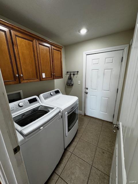 clothes washing area featuring cabinets, washer and dryer, and light tile patterned floors