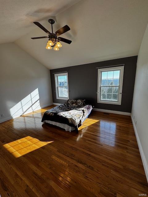 bedroom featuring dark wood-type flooring, ceiling fan, vaulted ceiling, and multiple windows