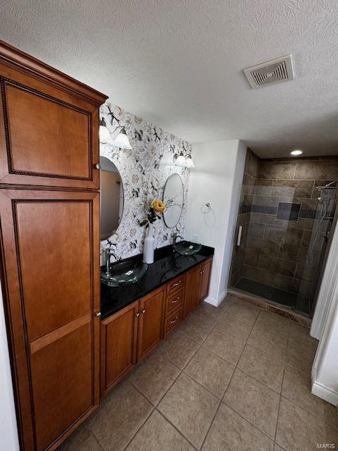 bathroom featuring tile patterned flooring, vanity, a textured ceiling, and walk in shower