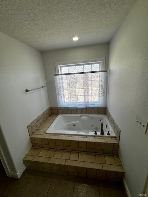 bathroom featuring tiled tub, tile patterned floors, and a textured ceiling