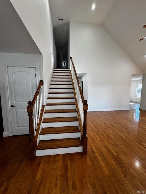 staircase featuring hardwood / wood-style flooring, ceiling fan, and high vaulted ceiling