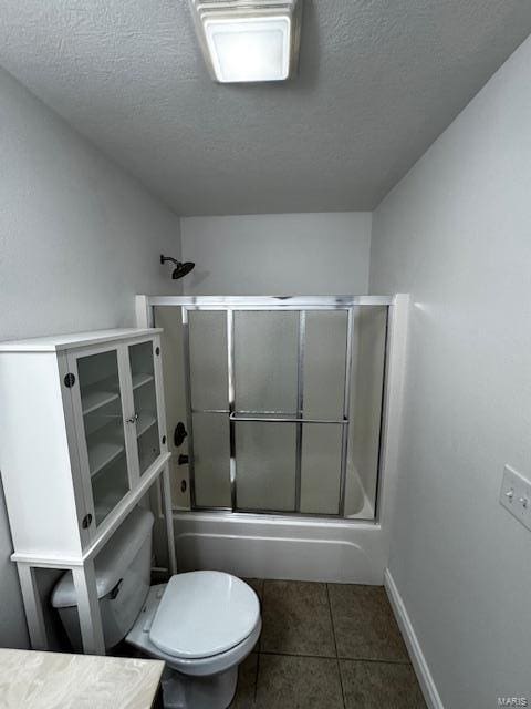 full bathroom featuring shower / bath combination with glass door, vanity, toilet, tile patterned floors, and a textured ceiling