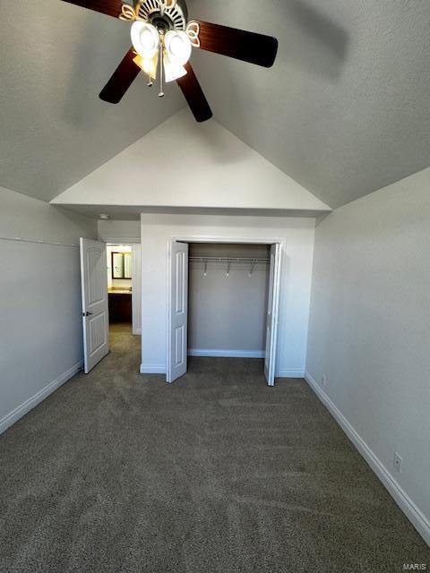 unfurnished bedroom with ceiling fan, lofted ceiling, a closet, and dark colored carpet