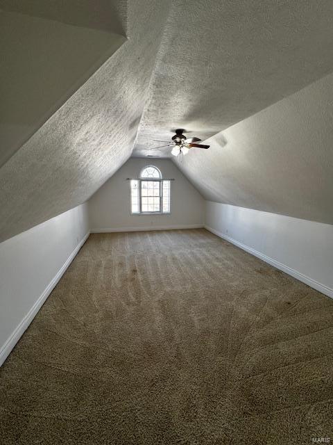 additional living space with ceiling fan, carpet floors, vaulted ceiling, and a textured ceiling