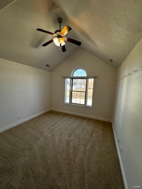 empty room with vaulted ceiling, ceiling fan, a textured ceiling, and dark carpet