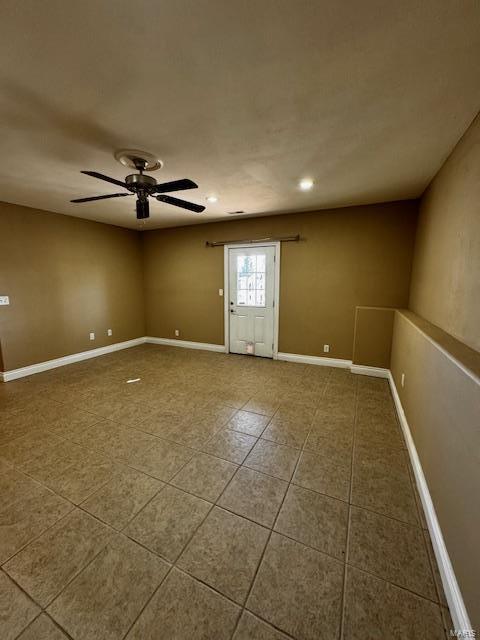 tiled empty room featuring ceiling fan