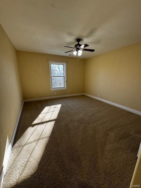 empty room with ceiling fan and dark carpet