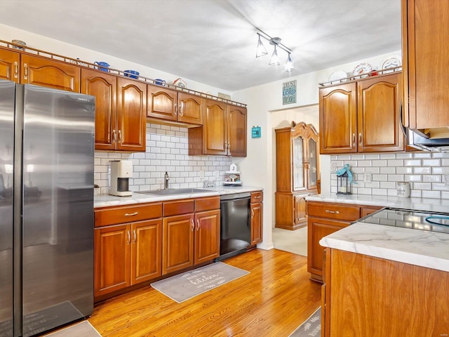 kitchen with sink, stainless steel fridge, black dishwasher, and light wood-type flooring