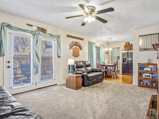 carpeted living room with ceiling fan with notable chandelier and a textured ceiling