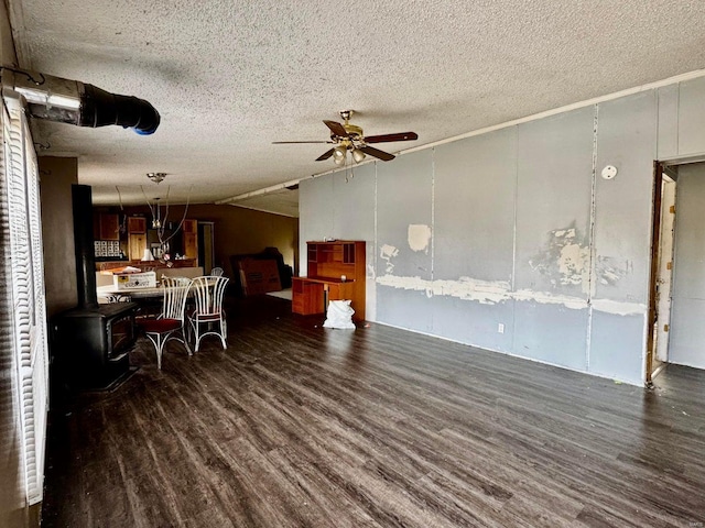 interior space with lofted ceiling, a wood stove, ceiling fan, dark wood-type flooring, and a textured ceiling