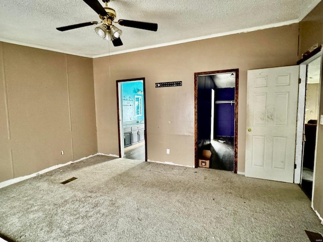 carpeted spare room featuring ceiling fan, ornamental molding, and a textured ceiling