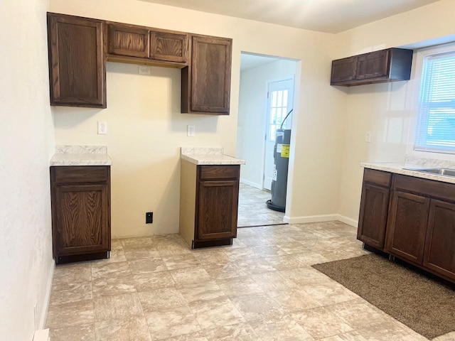 kitchen with dark brown cabinetry, sink, and water heater