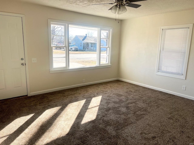 spare room with dark colored carpet, ceiling fan, and a textured ceiling