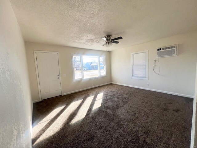 carpeted empty room featuring ceiling fan, a wall mounted air conditioner, and a textured ceiling