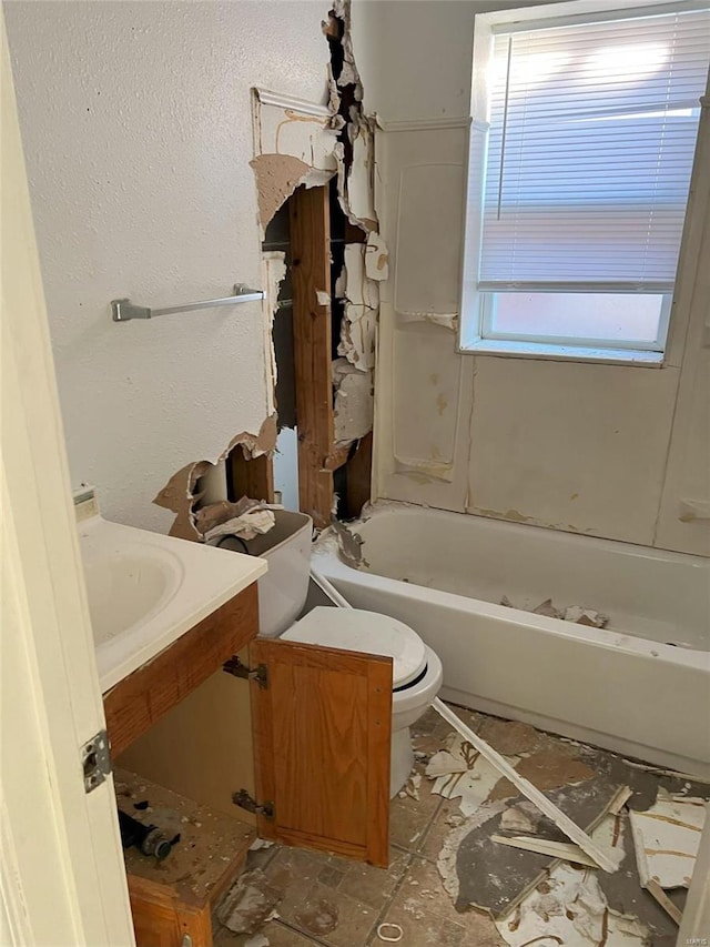 bathroom with vanity, toilet, and a tub