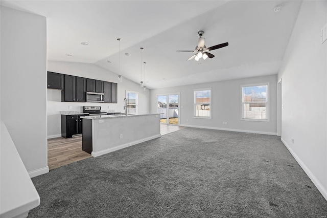 kitchen with stainless steel appliances, light colored carpet, open floor plan, a sink, and ceiling fan