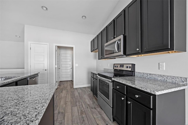 kitchen featuring dark wood-style flooring, stainless steel appliances, recessed lighting, dark cabinets, and baseboards