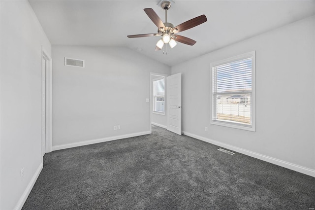 unfurnished bedroom featuring baseboards, visible vents, vaulted ceiling, and dark colored carpet