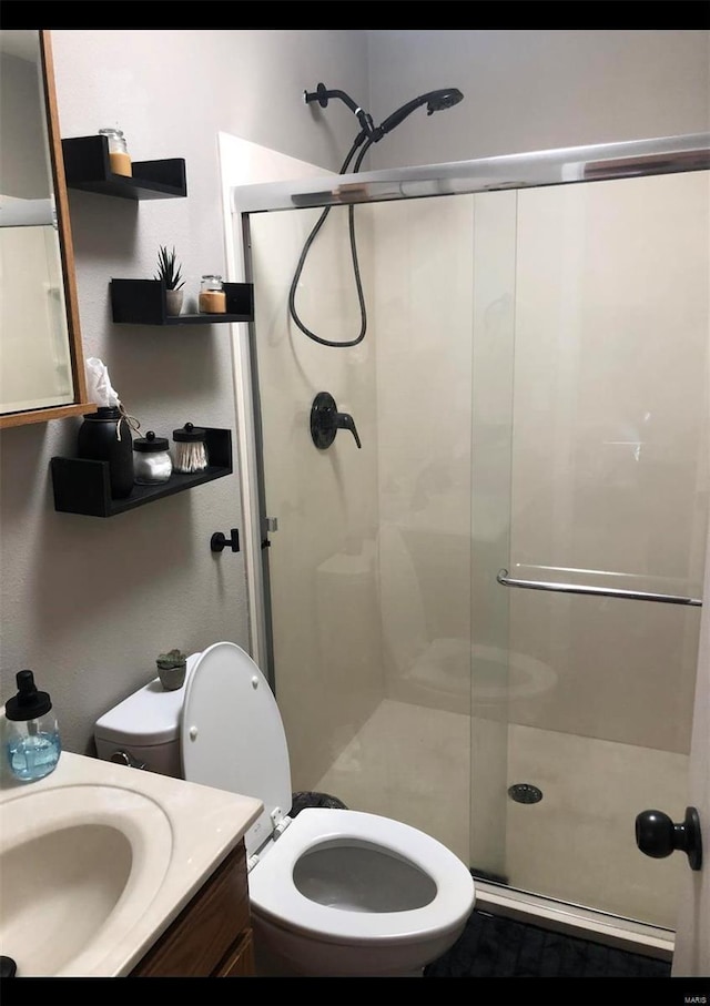 bathroom with a shower with door, vanity, and toilet