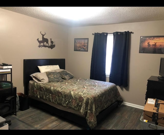 bedroom with dark hardwood / wood-style floors and a textured ceiling