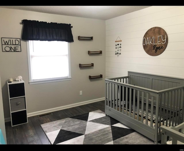 bedroom with a nursery area and dark hardwood / wood-style flooring