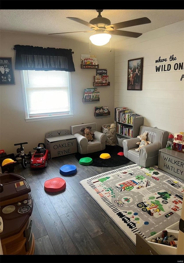 playroom with hardwood / wood-style flooring, ceiling fan, and a textured ceiling