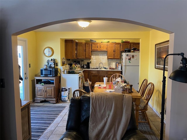 kitchen featuring light tile patterned flooring, tasteful backsplash, sink, white fridge, and electric stove