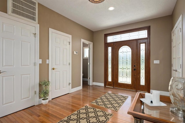 foyer entrance with light hardwood / wood-style flooring and a textured ceiling