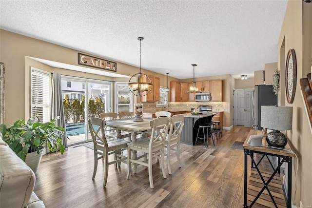 dining area with dark hardwood / wood-style floors, sink, a textured ceiling, and a notable chandelier