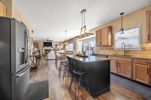 kitchen featuring sink, stainless steel appliances, a center island, light stone countertops, and a kitchen bar