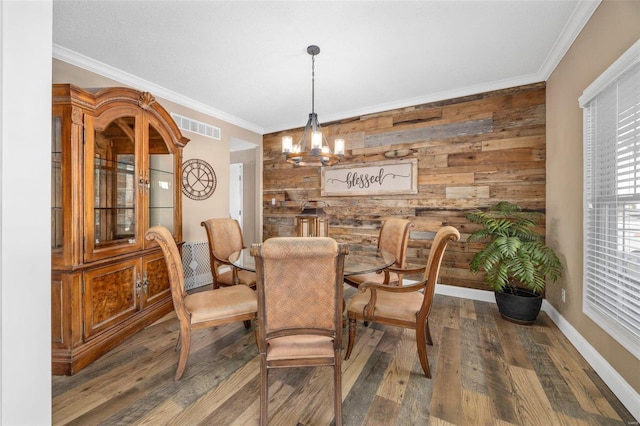 dining space with ornamental molding, dark hardwood / wood-style floors, an inviting chandelier, and wood walls