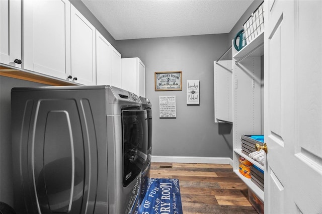 laundry room featuring dark wood-type flooring, cabinets, washing machine and dryer, and a textured ceiling