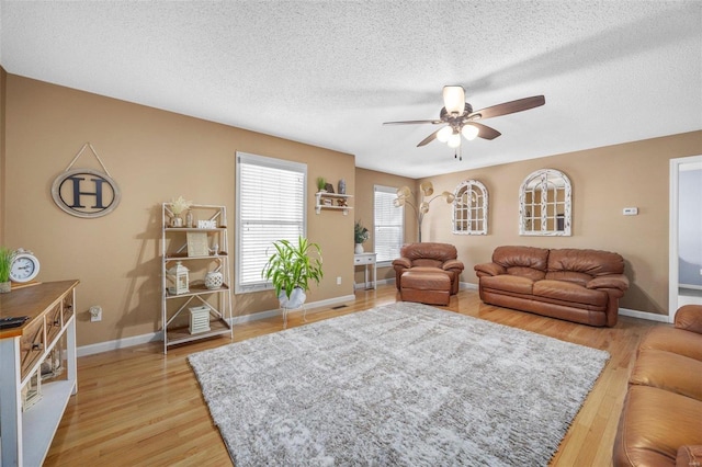 living room featuring a textured ceiling, ceiling fan, and light wood-type flooring