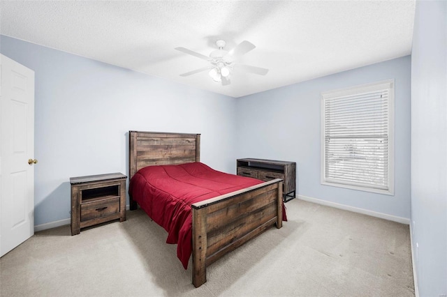 bedroom featuring ceiling fan, light colored carpet, and a textured ceiling