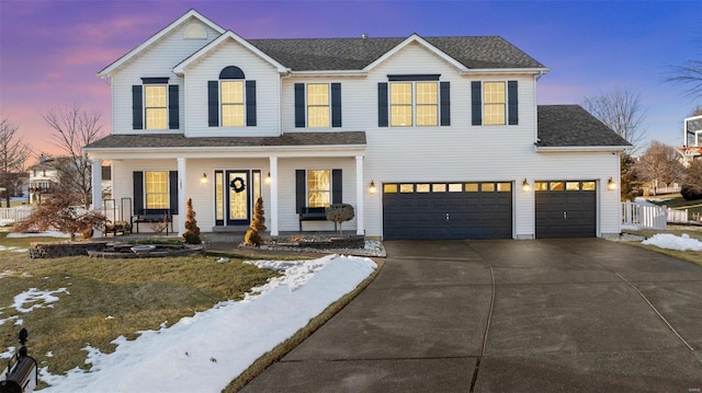 view of front of property featuring a garage, a yard, and covered porch