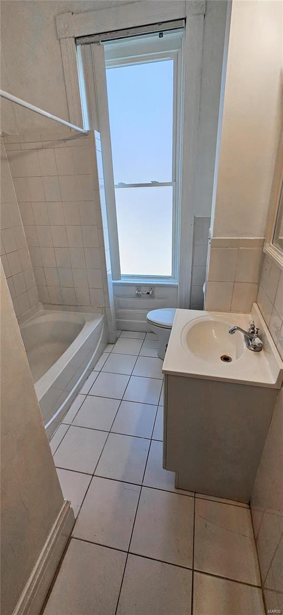 bathroom featuring tile patterned floors, toilet, a bathing tub, and vanity