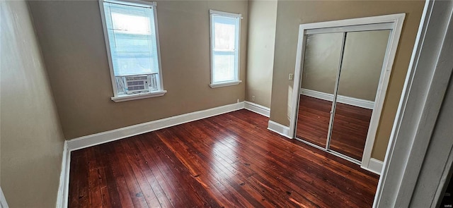 unfurnished bedroom featuring dark hardwood / wood-style flooring, cooling unit, and a closet