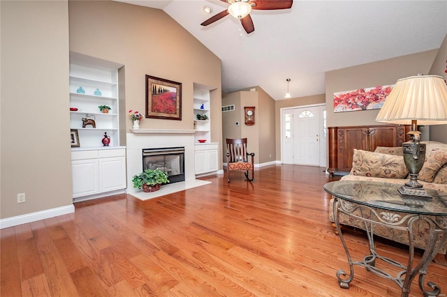 living room featuring ceiling fan, lofted ceiling, light hardwood / wood-style floors, and built in shelves