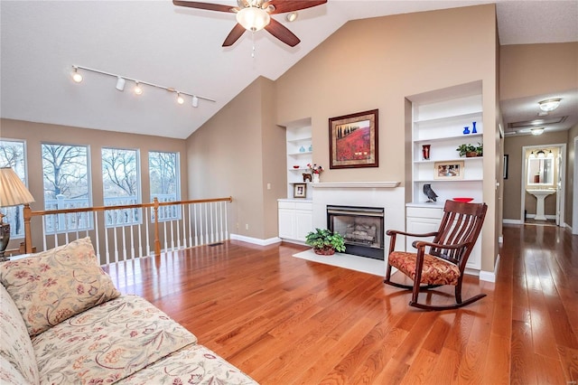 living room with hardwood / wood-style flooring, track lighting, high vaulted ceiling, and built in features