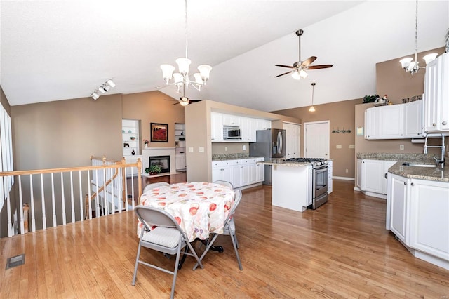 dining space featuring ceiling fan with notable chandelier, lofted ceiling, sink, track lighting, and light hardwood / wood-style flooring