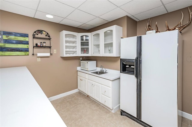 kitchen featuring white cabinetry, sink, white appliances, and a drop ceiling