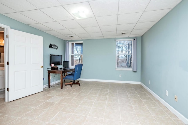 tiled office space featuring a drop ceiling and a healthy amount of sunlight