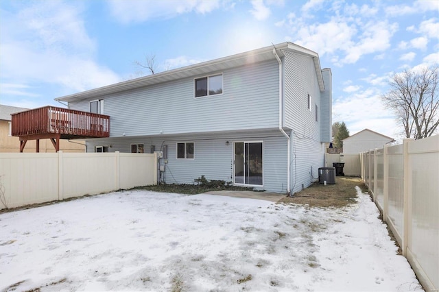 snow covered property with central AC and a deck