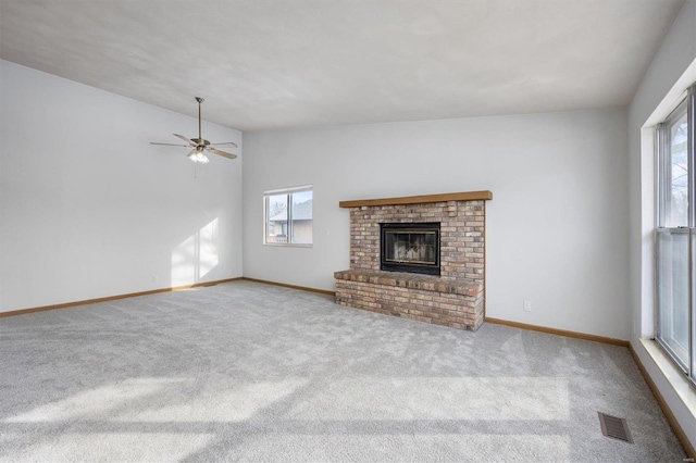 unfurnished living room with lofted ceiling, ceiling fan, a fireplace, and light carpet