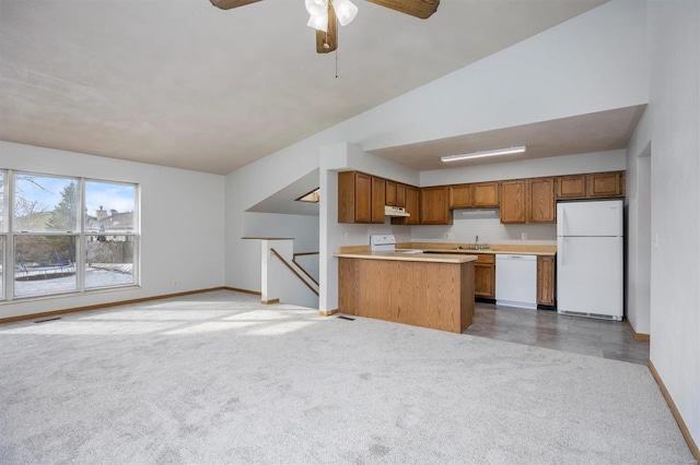 kitchen featuring sink, white appliances, carpet flooring, vaulted ceiling, and kitchen peninsula