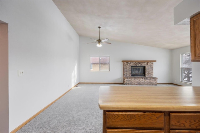 interior space with lofted ceiling, a fireplace, light colored carpet, and ceiling fan