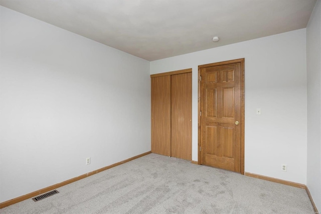 unfurnished bedroom featuring a closet and light carpet