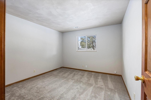 empty room with light colored carpet and a textured ceiling