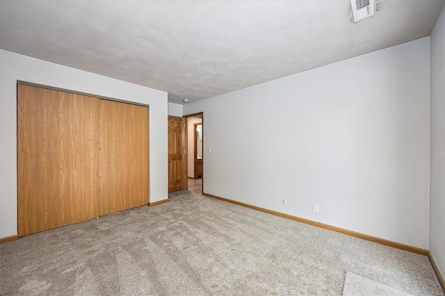 unfurnished bedroom featuring light carpet and a closet