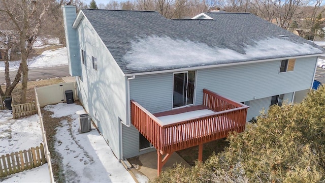 snow covered back of property with cooling unit and a deck